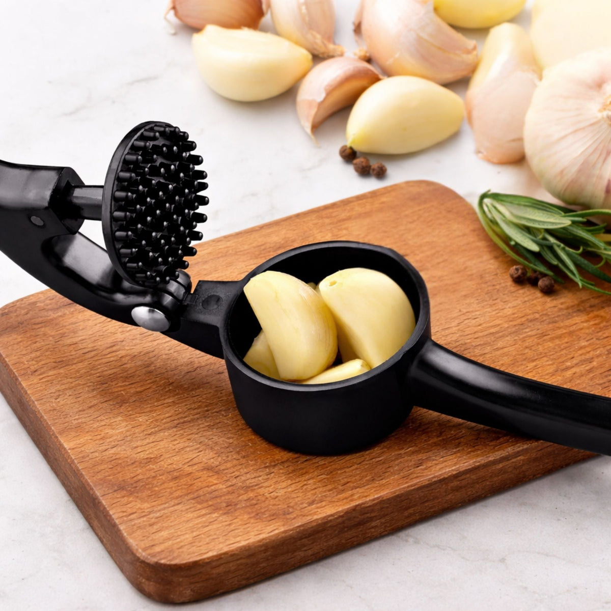Garlic press with pressed garlic cloves on a wooden cutting board with garlic and herbs in the background.